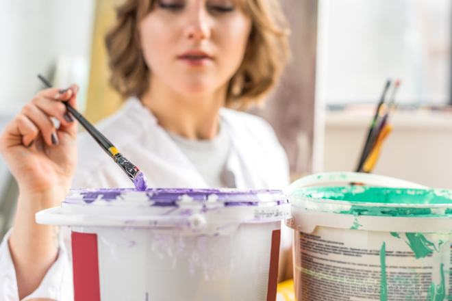 fille avec un pinceau et des pots de peinture